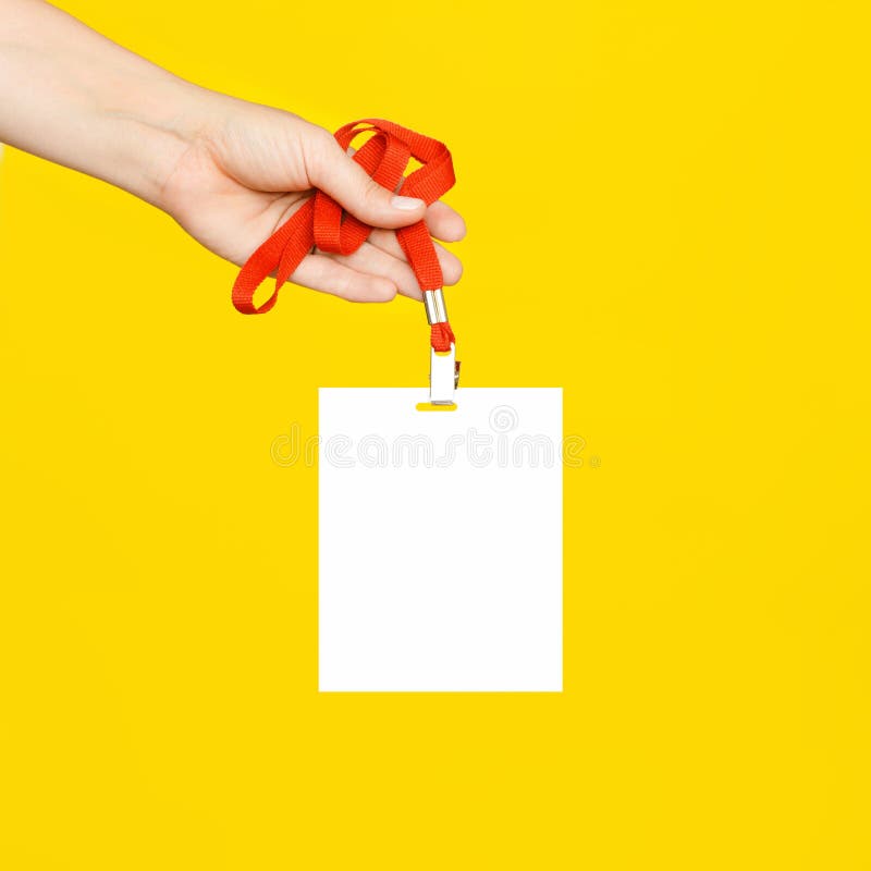The woman`s hand holds a clean white badge on a red cord on yellow background. royalty free stock photos The woman`s hand holds a clean white badge on a red cord on yellow background. royalty free stock photos
