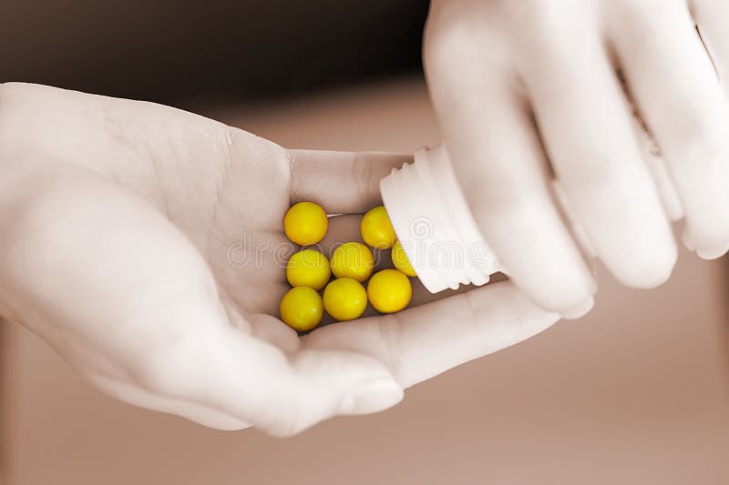 A woman`s hand holds a medicine and pours yellow pills into her hand from a bottle in close-up. Hands of a young girl holding a white jar with round vitamins. The concept of health, homeopathy..