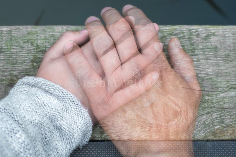 Semi-transparent man`s hand on a woman`s hand as a sign of farewell by separation or death