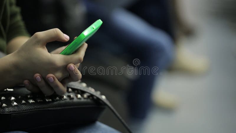 Woman's hand with pink nails, typing SMS on your phone.