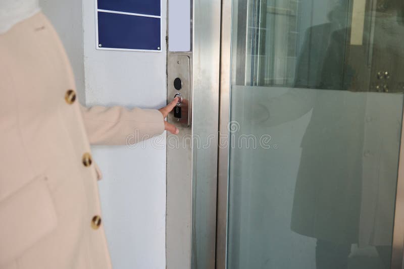 A woman& x27;s hand presses the elevator call button. Close-up unrecognizable person pushing up arrow elevator button stock photos