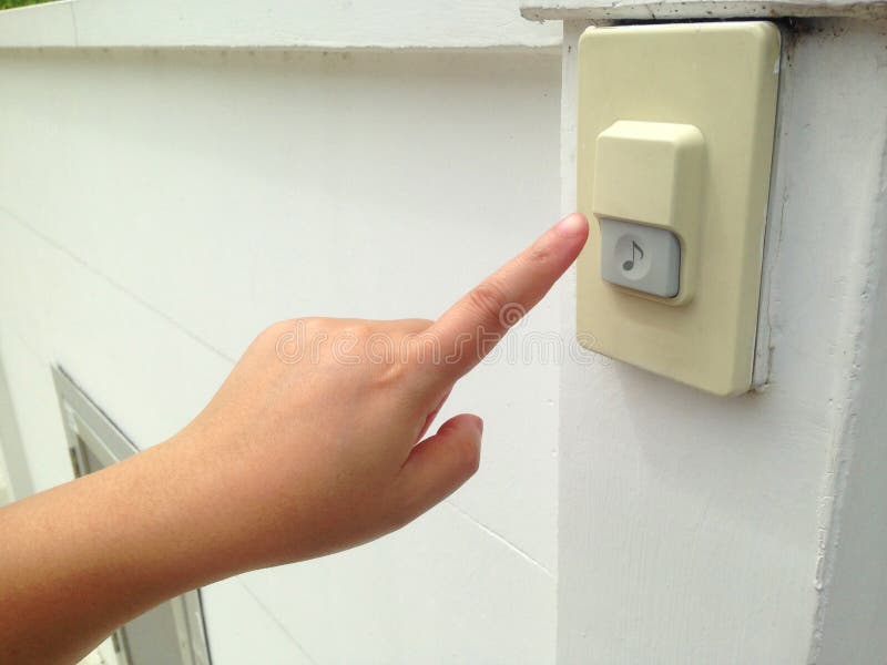 Woman`s hand push the doorbell in front of house.