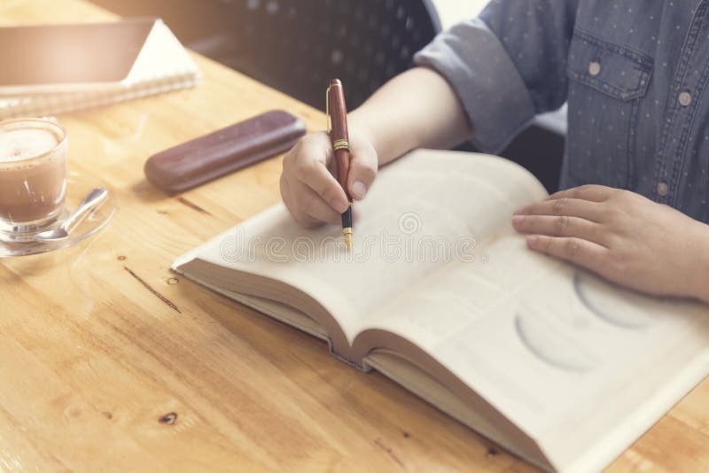 Woman S Hand Reading Book With Pen, Tablet And Notebook