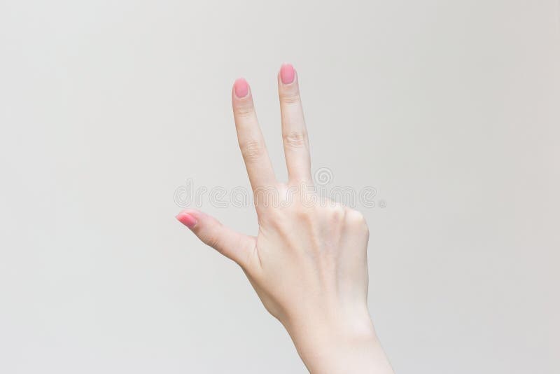 Womanâ€™s hand shows up three fingers as number three on white background