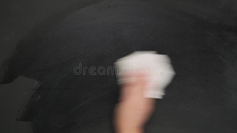 Woman`s hand wipes a black chalk board with a white rag