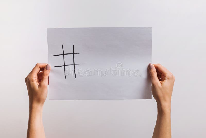 Woman`s hands holding a paper with drawn hashtag symbol and some copy space on it royalty free stock photos