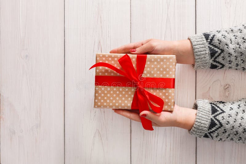 Woman`s hands wrapping christmas holiday present with red ribbon