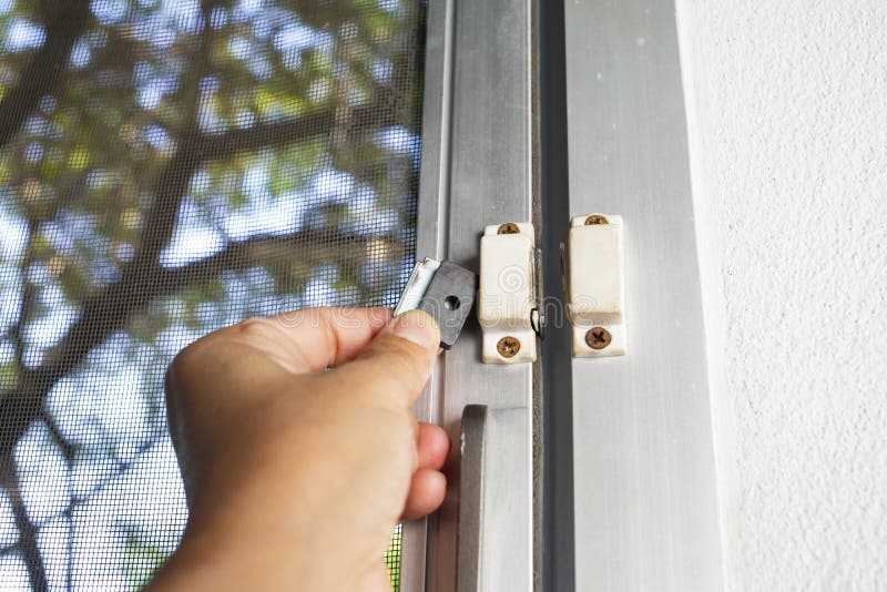 Woman hands holding broken security magnetic lock  contact for mosquito wire screen window, Repair Room concept, Close up shot