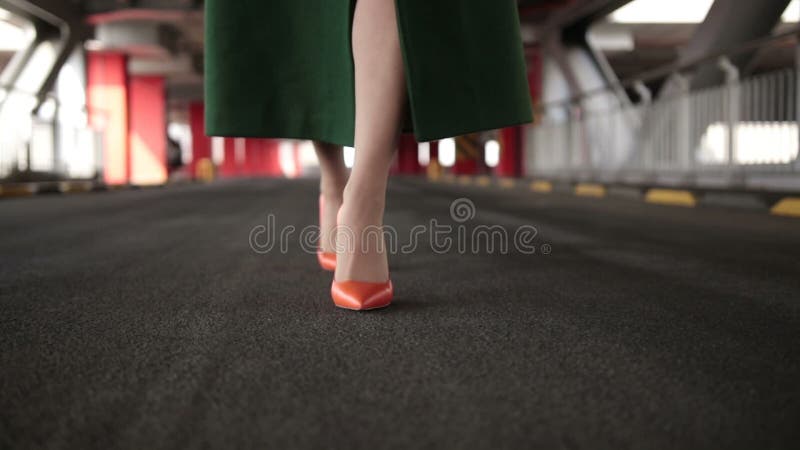 Woman`s legs in high heel shoes walking on road