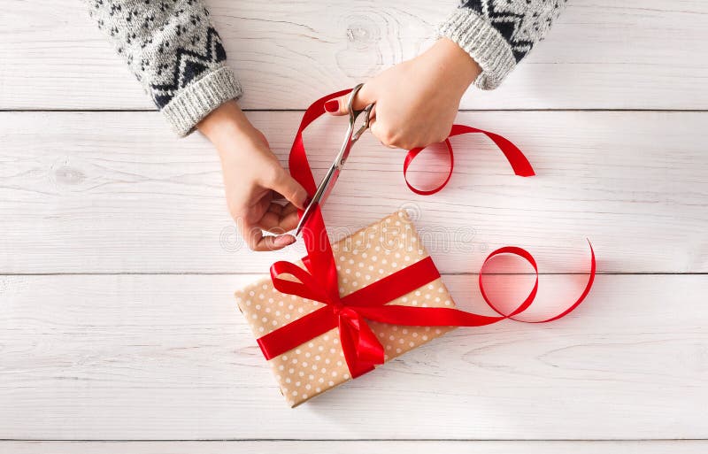 Woman& x27 ; s remet envelopper le ruban de rouge d'iwith de présent de vacances de Noël photos libres de droits Woman& x27 ; s remet envelopper le ruban de rouge d'iwith de présent de vacances de Noël photos libres de droits
