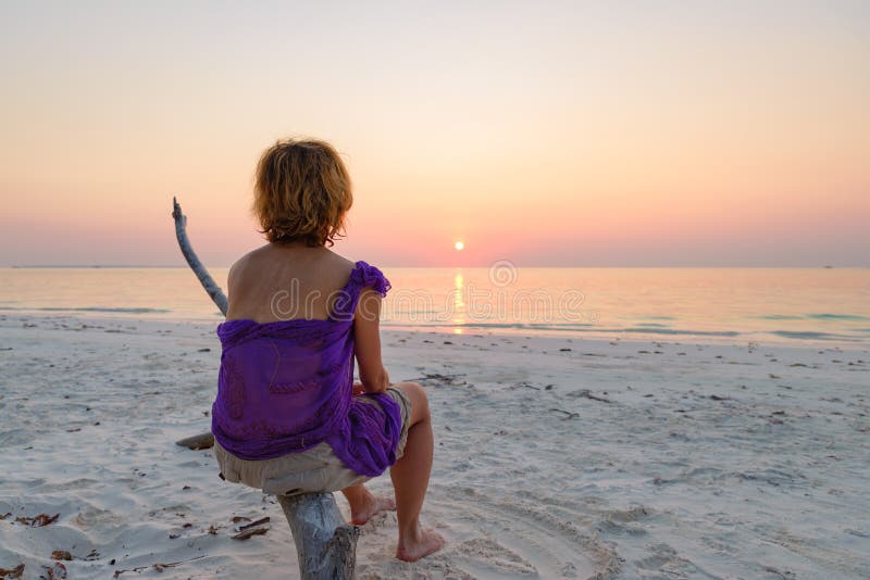 Woman on sand beach romantic sky at sunset, rear view silhouette, golden sunlight, real people. Indonesia, Kei islands, Moluccas Maluku