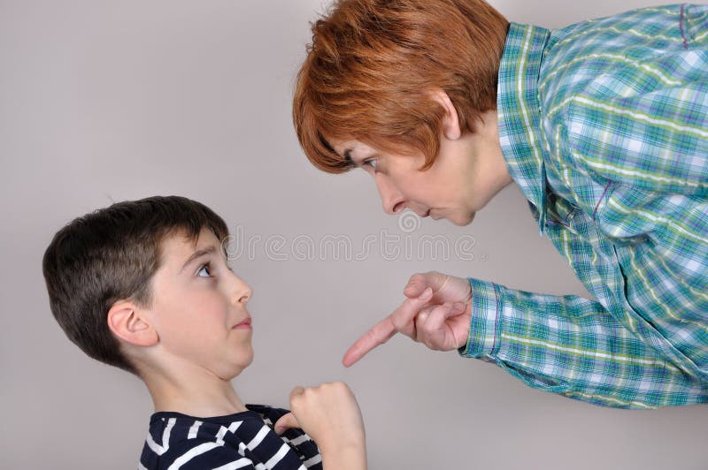 Woman scolding and pointing her index finger at the scared young boy. Woman scolding and pointing her index finger at the scared young boy