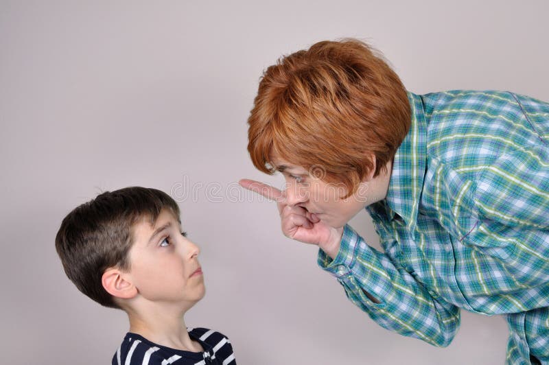 Woman scolding and pointing her index finger at the scared young boy. Woman scolding and pointing her index finger at the scared young boy