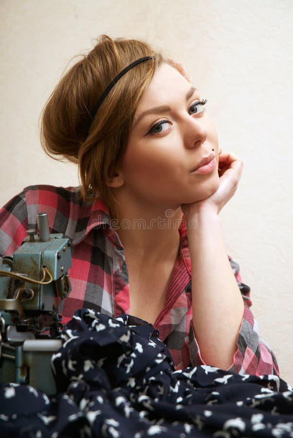 Woman seamstress posing near sewing machine