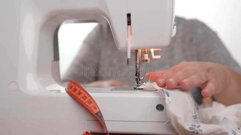 Woman seamstress sews on sewing machine.