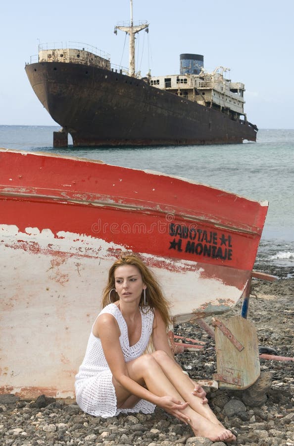 Woman in the seaside near an abandoned ship