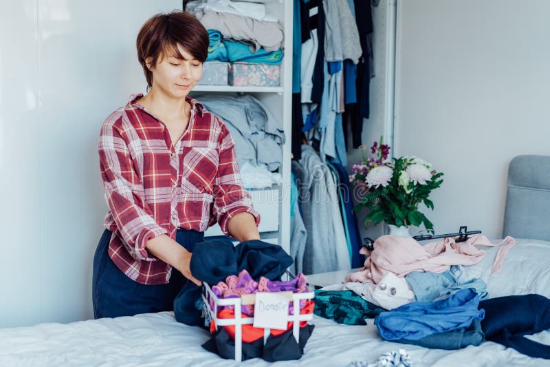 Woman selecting clothes from her wardrobe for donating to a Charity shop. Decluttering, Sorting clothes and Cleaning Up royalty free stock photography