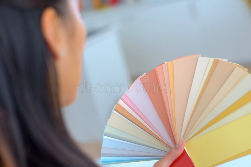 Woman Selecting Home Interior Paint Color from Swatch Catalog Stock