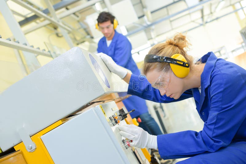 Woman setting up machine in factory