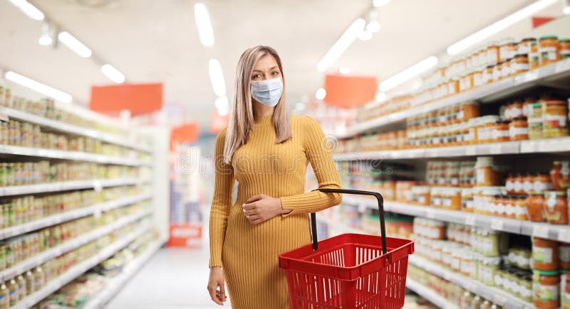 Woman with a shopping basket wearing a protective face mask in a store