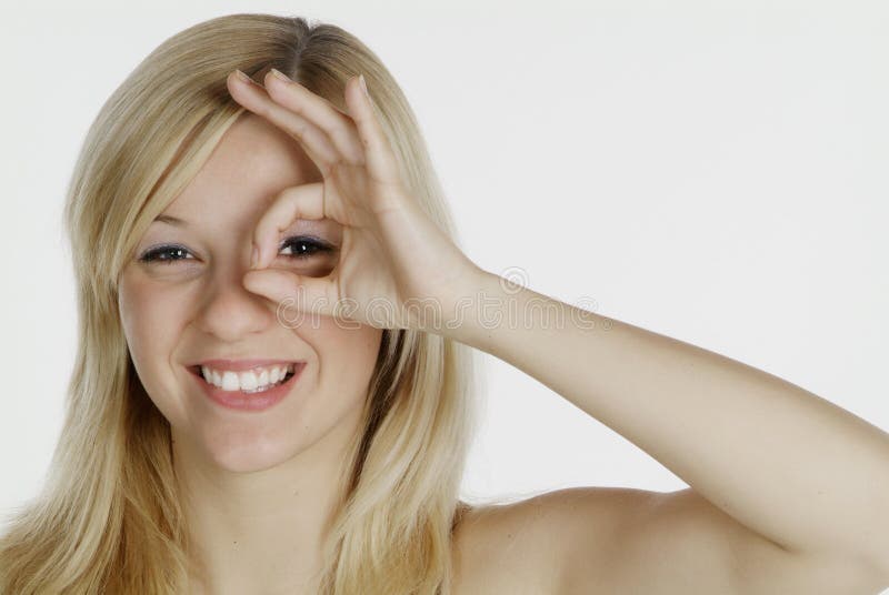 Freundliche Frau mit blonden Haaren sieht durch das Loch suchen von Ihren finger.