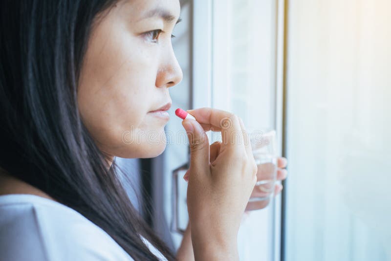 Woman sick with capsules putting in her mouth,female taking medicines and a glass of water,Concept for health royalty free stock image Woman sick with capsules putting in her mouth,female taking medicines and a glass of water,Concept for health royalty free stock image