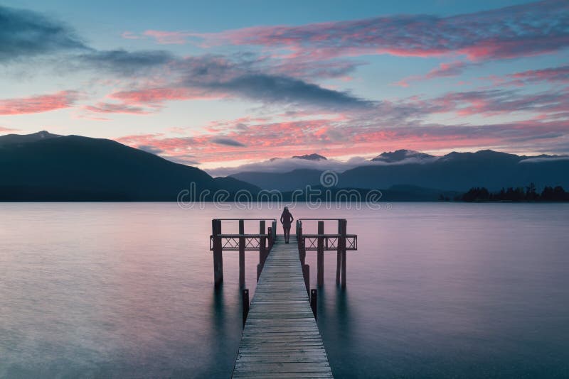 Woman Silhouette in Romantic wharf on Te Anau on South Island of New Zealand Beautiful pier on sunrise. Lake Te Anau.