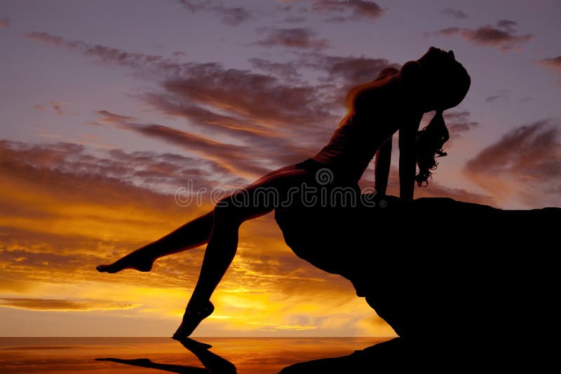 Woman silhouette by water sunset