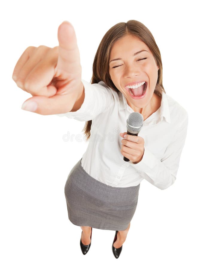 Fun high angle view of a passionate attractive young woman holding a microphone singing or making a point during a speech gesturing and pointing her finger at the camera isolated on white. Fun high angle view of a passionate attractive young woman holding a microphone singing or making a point during a speech gesturing and pointing her finger at the camera isolated on white