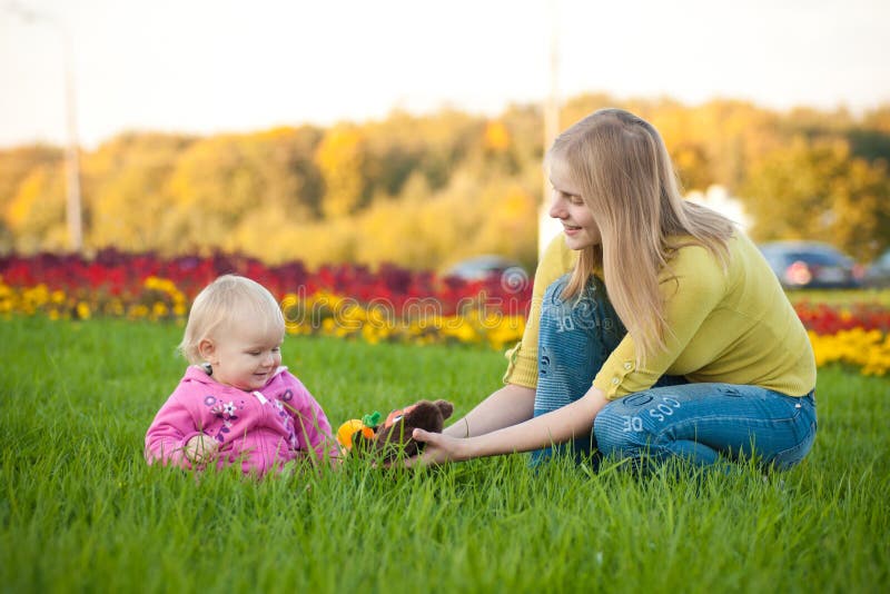 Woman sit on green grass near beds of flowers