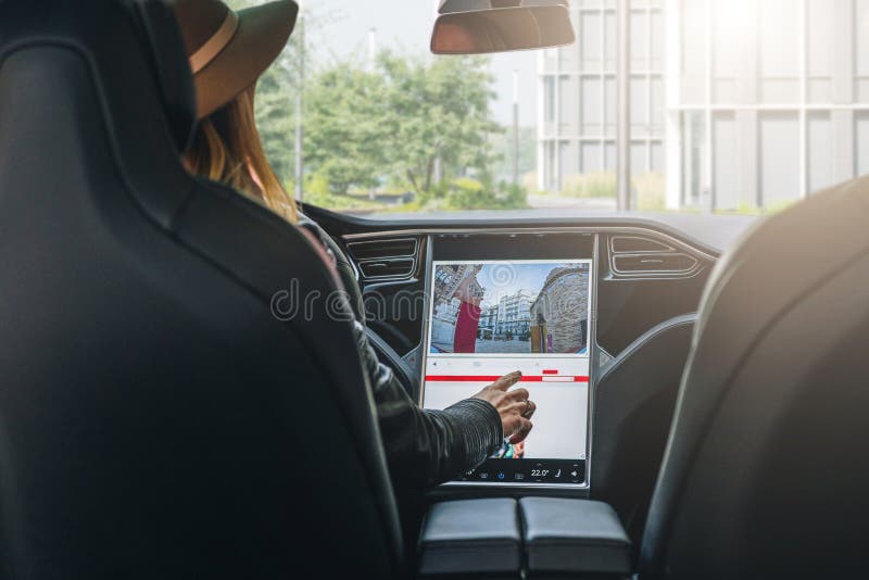 Woman sits behind wheel in car and uses electronic dashboard. Girl traveler looking for way through navigation system.