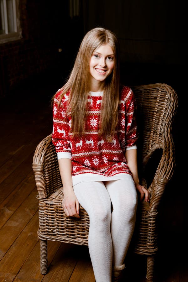 Woman sits in a chair wearing a sweater with the r