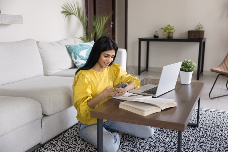 Woman distracted from studying process using smartphone royalty free stock photography
