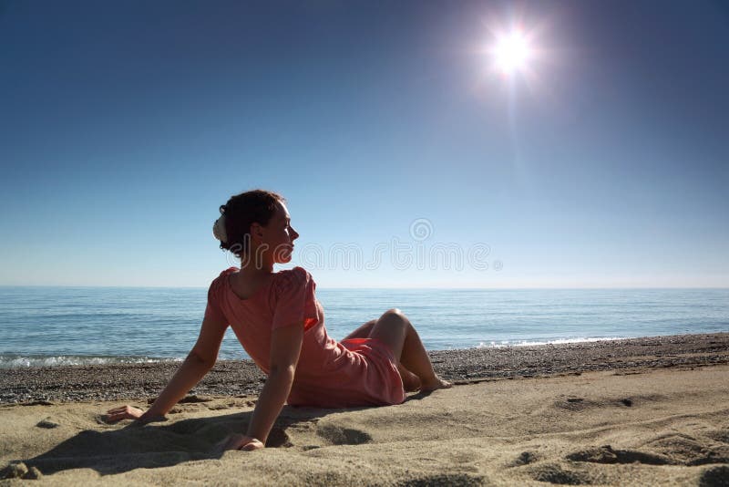 Woman sits on sand near sea