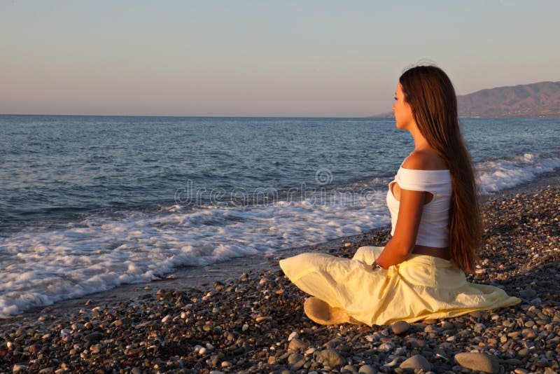 A woman is sitting on a beach