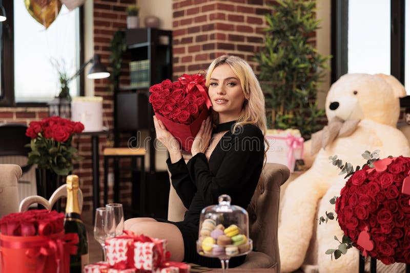 Woman sitting beside big bear gift holding red roses bouquet