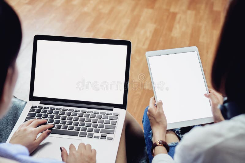 Woman sitting on black sofa using computer and blank screen tablet. Blank screen for the graphics.