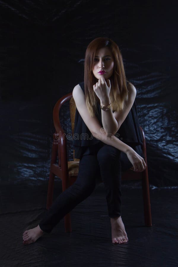 Woman Sitting on Brown Chair With Black Background stock photos Woman Sitting on Brown Chair With Black Background stock photos