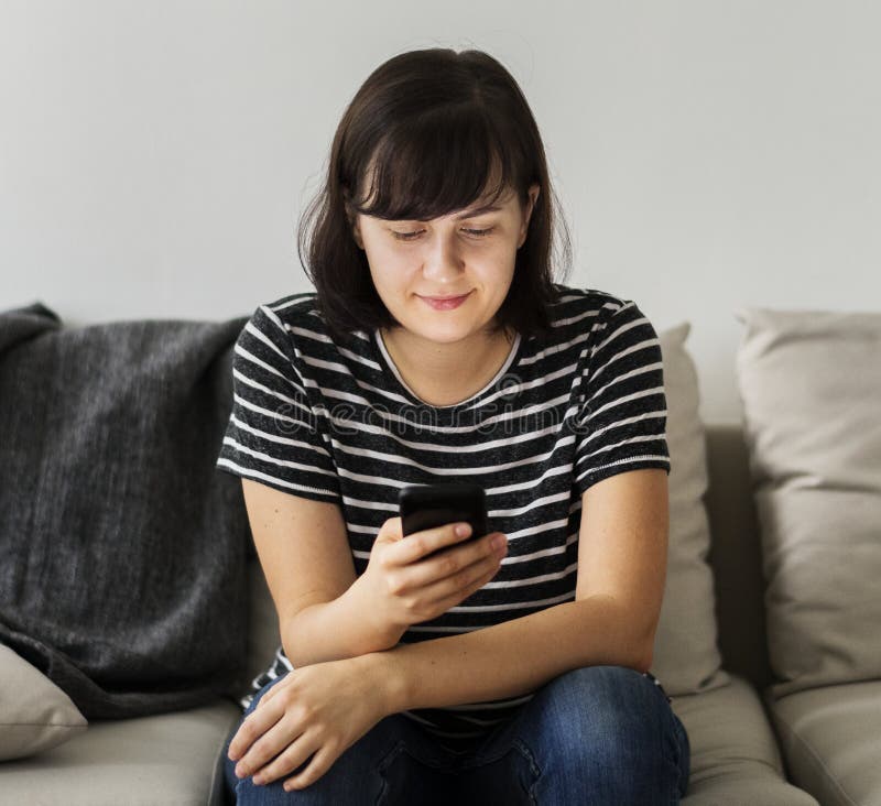 Woman sitting on a couch using smartphone royalty free stock images