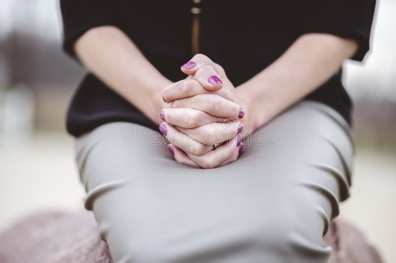 Woman Sitting With Hands Together On Lap While Praying Stock Photo