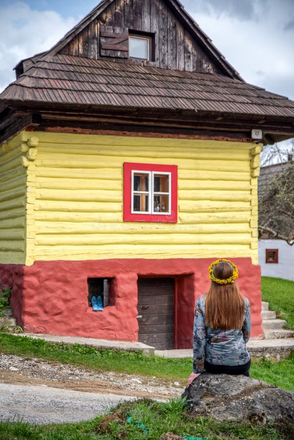 Woman sitting and looking on colorful wooden cottage in historical village Vlkolinec at Slovakia