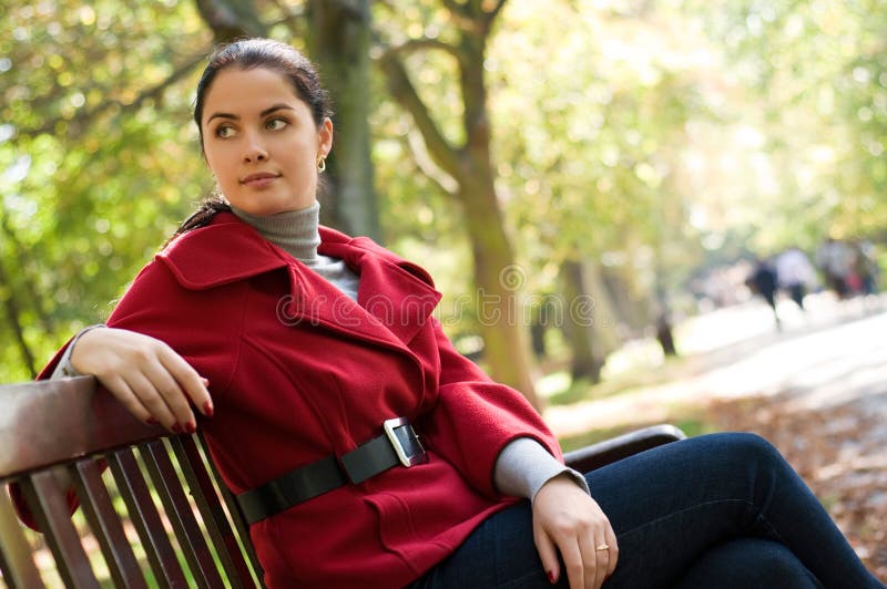 Woman sitting in a park on a wooden bench