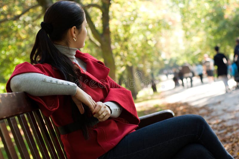 Woman sitting in a park on a wooden bench