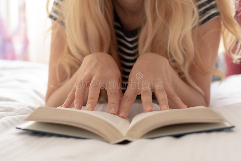 Woman sitting relaxed on the bead reading a book