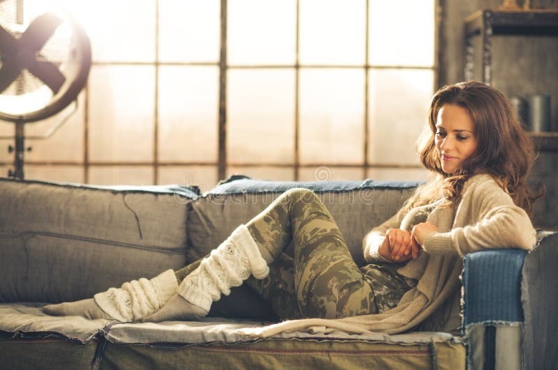 Woman sitting on sofa in loft relaxing