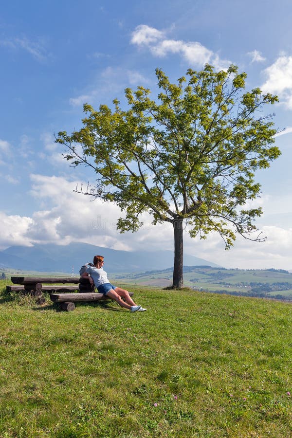 Žena sedící na letním kopci poblíž Liptovského Trnovce, Slovensko.