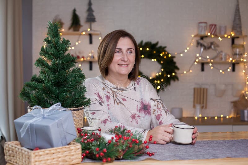 A woman sitting at a table and drinking hot chocolate in christmas decorated room royalty free stock image