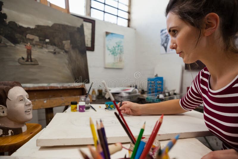 Attentive woman sketching on canvas in drawing class