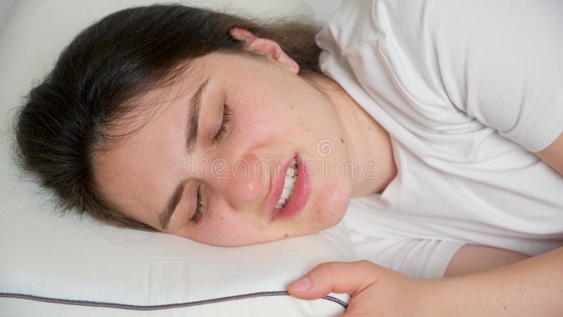 A woman sleeps and grinds her teeth in her sleep. Restless sleep, abrasion of teeth in a dream