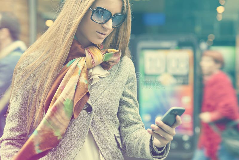 Woman with smartphone walking on street stock image